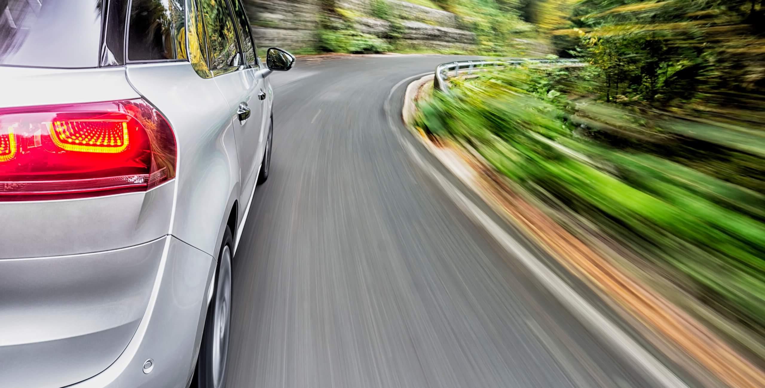 side view of a car driving on a curved road